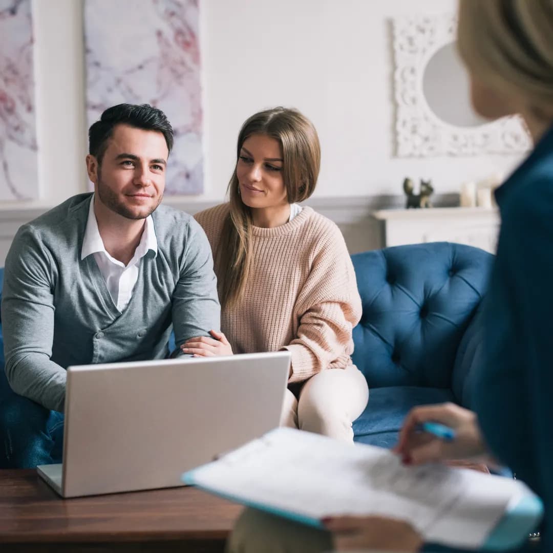 Jeune couple examinant une assurance emprunteur avec un conseiller pour leur prêt immobilier.
