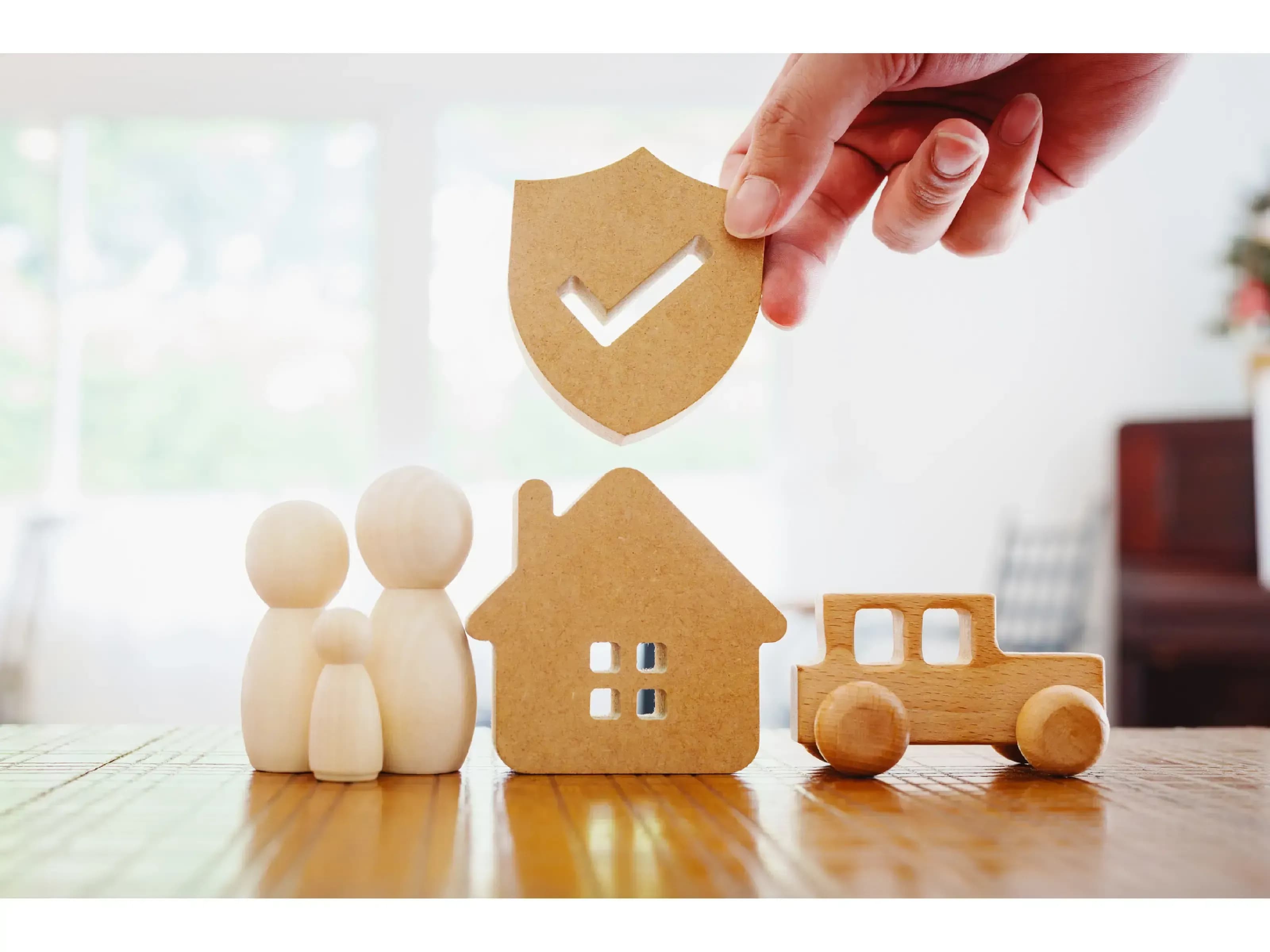 Symbole de protection financière : famille, maison, voiture et assurance, illustrant les garanties liées à l’assurance emprunteur.