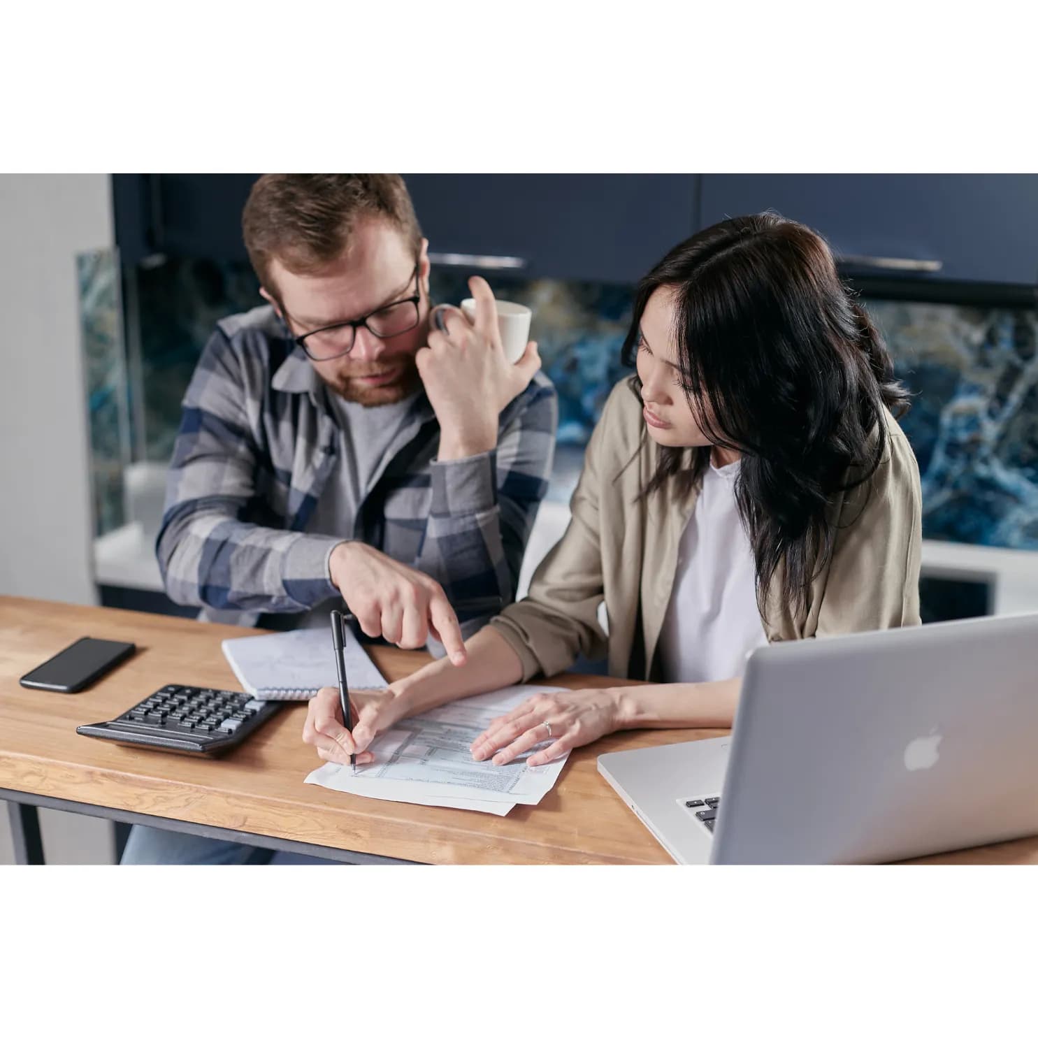 Un couple analyse ses finances avec une calculatrice et un ordinateur portable pour estimer leur capacité d’emprunt immobilier.